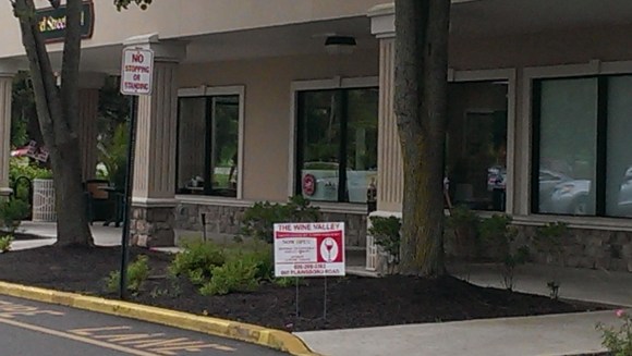 The sign is in front of Bagel Street fifty feet away, not in front of the Wine Valley store.